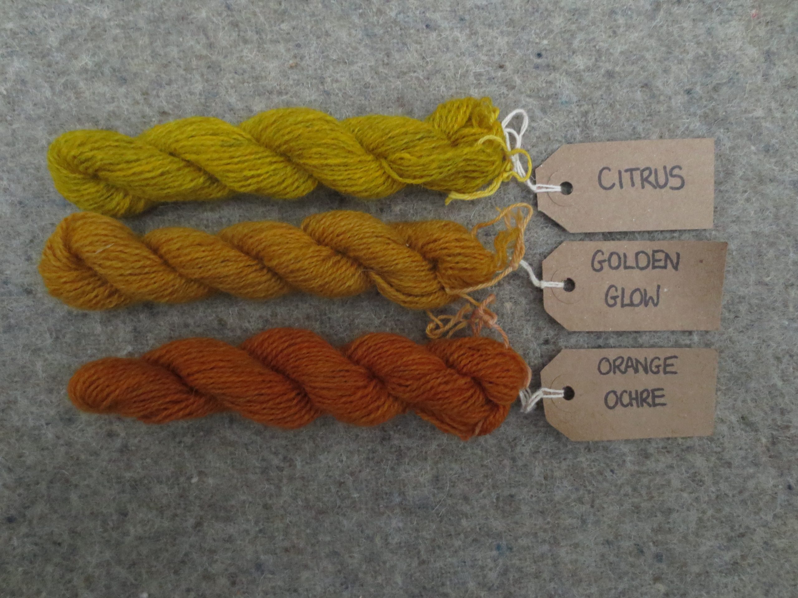 3 wool skeins labelled citrus, golden glow and orange ochre