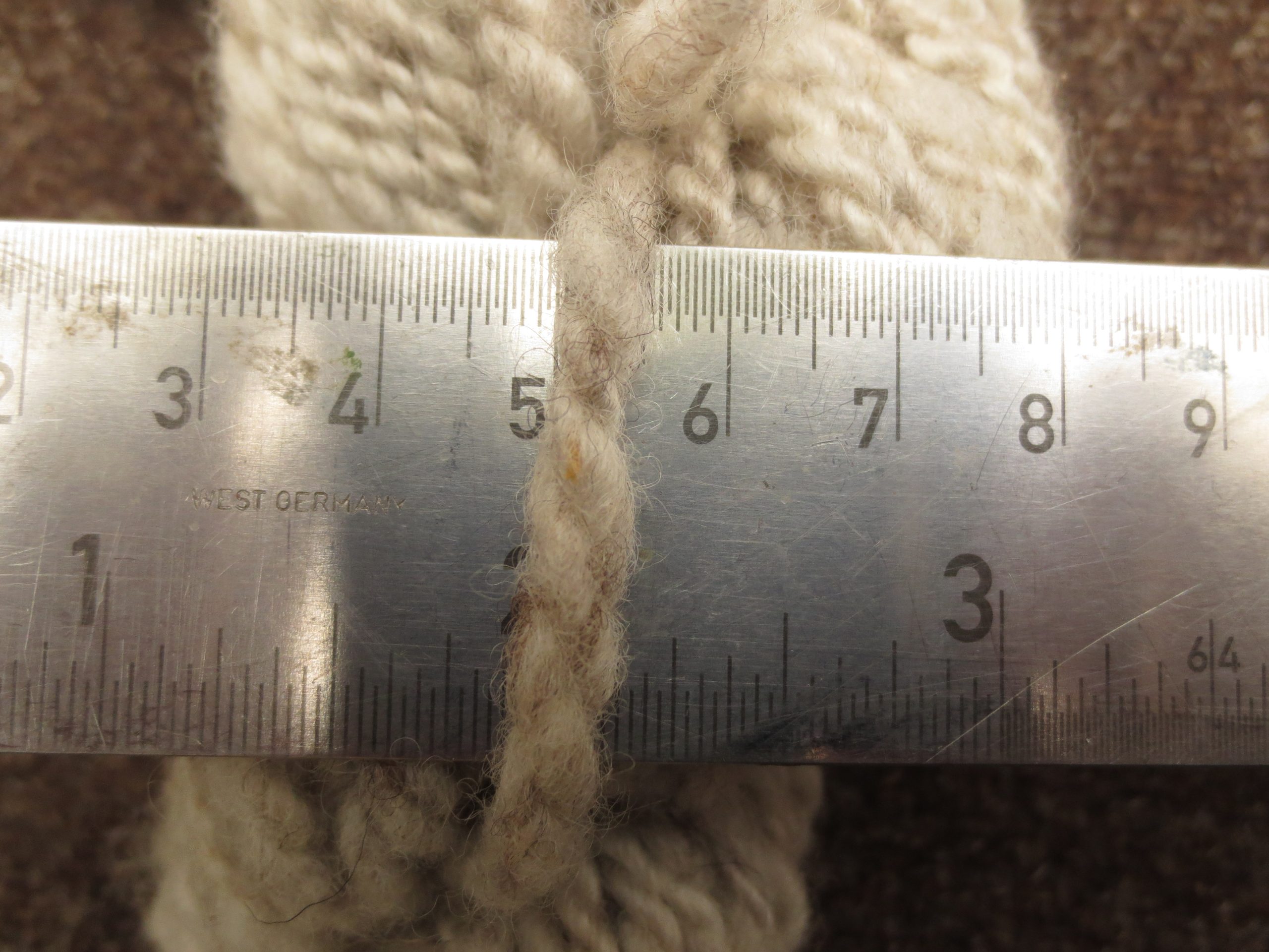 Close up with ruler of light grey skein, showing wool is approx 5mm thick