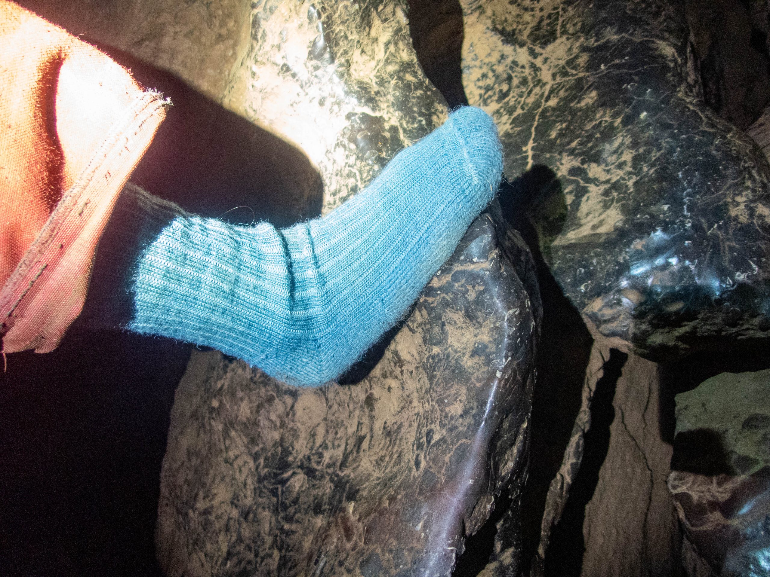 wool sock on a cavers foot on a rock