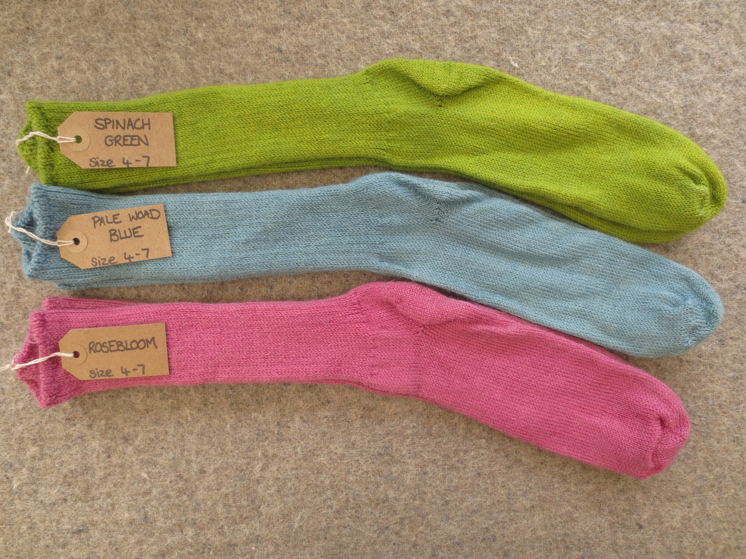 3 pairs of socks labelled Spinach Green, Pale Woad Blue and Rosebloom