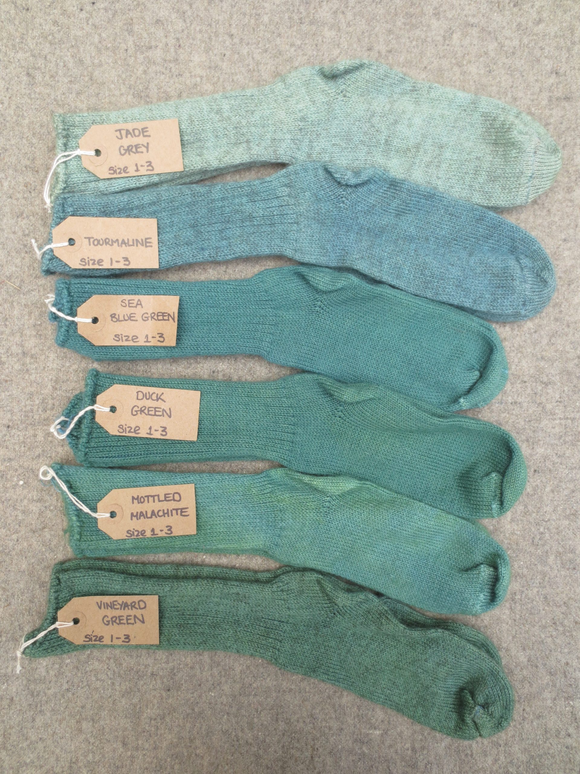 6 pairs of wool socks labelled jade grey, tourmaline, sea blue green, duck green, mottled malachite, vineyard green