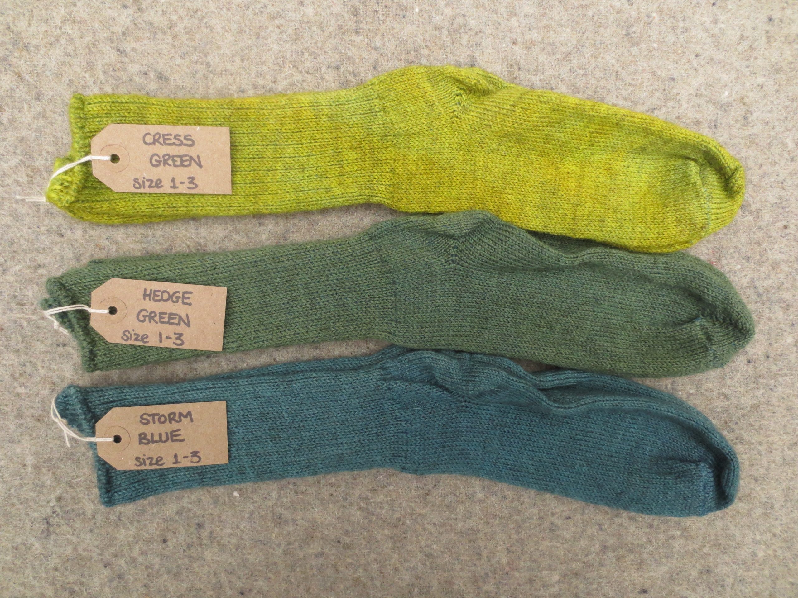 3 pairs of wool socks labelled cress green, hedge green and storm blue