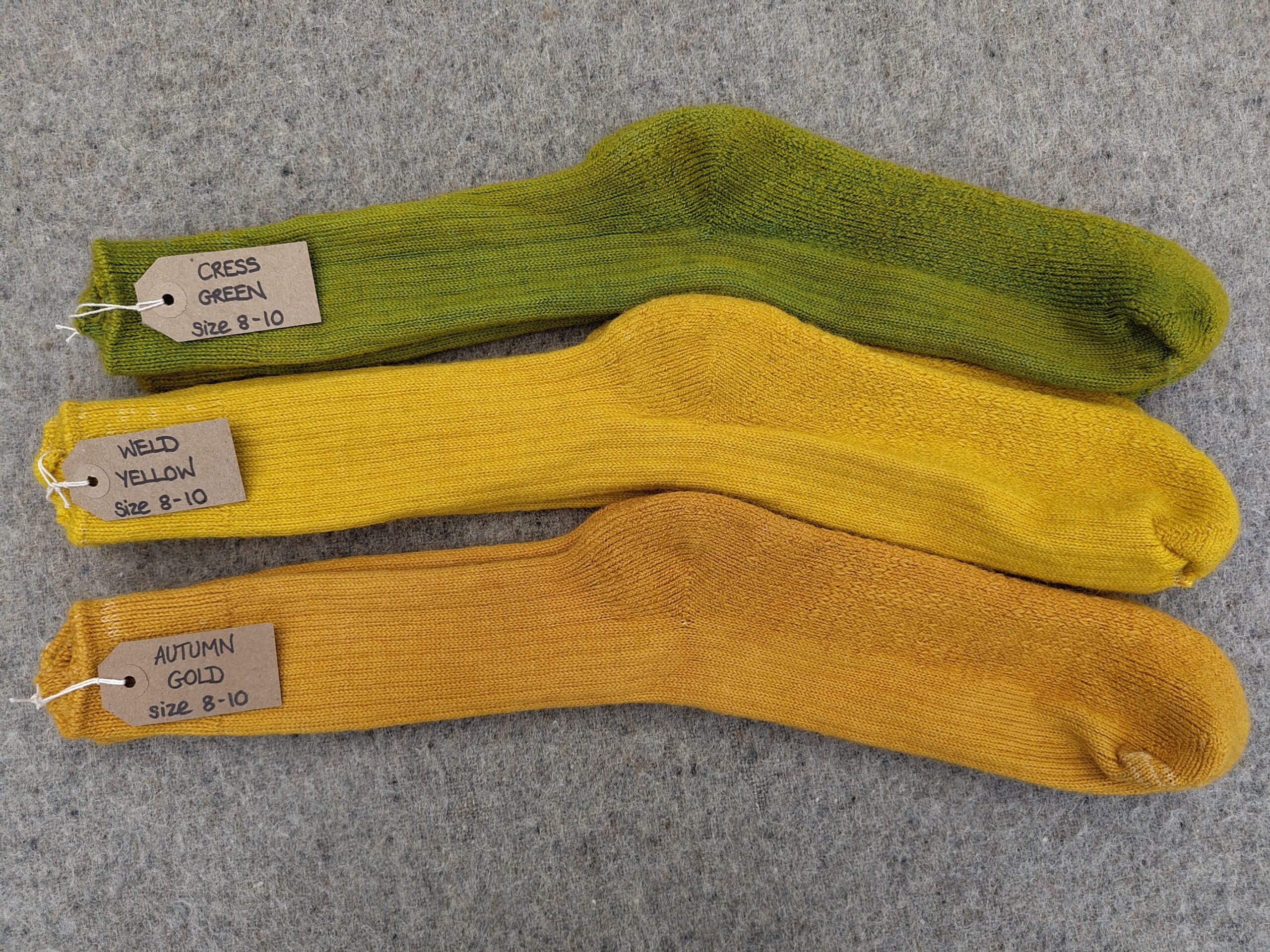 3 pairs of socks labelled Cress Green, Weld Yellow and Autumn Gold