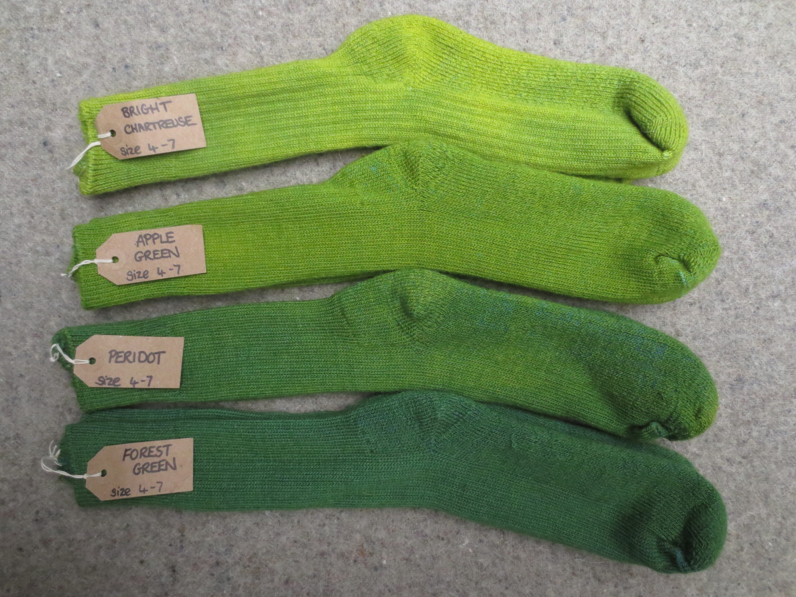 4 pairs of socks labelled Bright Chartreuse, Apple Green, Peridot, Forest Green